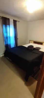 a bedroom with a bed with a black comforter and a window at Picon Homey in Springfield