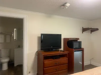 a room with a television on a wooden dresser with a toilet at River Valley Inn in Hatfield