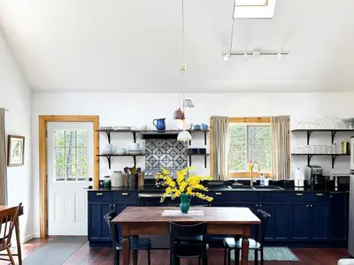 a kitchen with blue cabinets and a wooden table at Serene Retreat on a Stream in Phoenicia