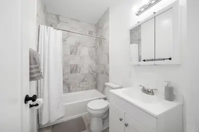 a white bathroom with a toilet and a sink at Big City Living: Elegant Apartment with NYC Vibes in Jersey City