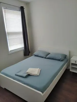 a bedroom with a bed with blue sheets and a window at NYC HomeBnB in Jersey City