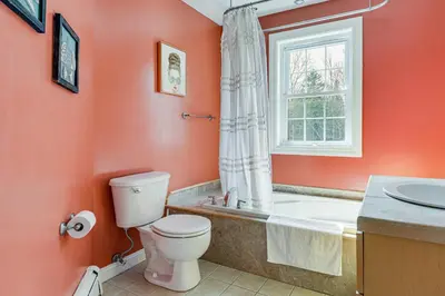 a bathroom with a toilet and a tub and a window at 6 Mi to Mt Snow Nature-View Home with Fire Pit! in West Dover