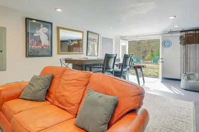 an orange couch in a living room with a table at 6 Mi to Mt Snow Nature-View Home with Fire Pit! in West Dover