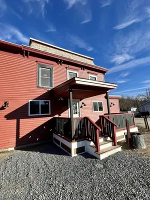 a red house with a front porch and a bench at Berkshires Studio Apartment at the Stephentown Hotel in Hancock