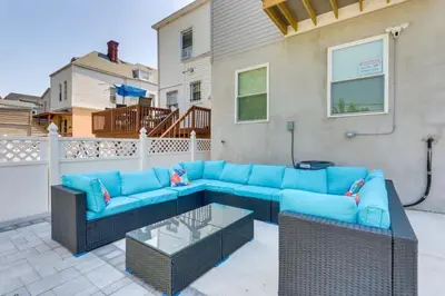 a patio with a blue couch and wicker chairs at Modern City Getaway Near Downtown Newark & NYC in Newark