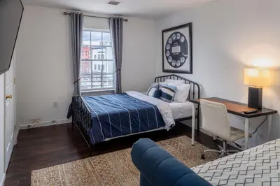 a bedroom with a bed and a desk and a bed and a window at Huge 3BR Urban Gem just 3 miles to NYC plus Free Parking in Jersey City