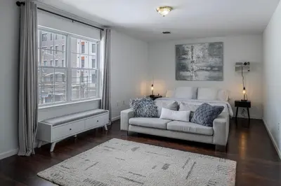a bedroom with a bed and a couch and a window at Huge 3BR Urban Gem just 3 miles to NYC plus Free Parking in Jersey City