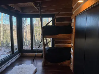 a room with a bunk bed in a cabin with windows at Casa Del Rio in Margaretville
