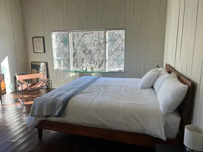 a bedroom with a bed with white sheets and a window at Casa Del Rio in Margaretville