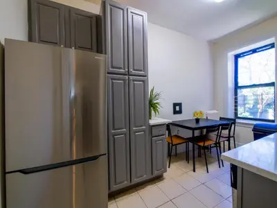 a kitchen with a stainless steel refrigerator and a table at Charming 1BR Apartment Near NYC Ideal for Urban Explorers in Jersey City