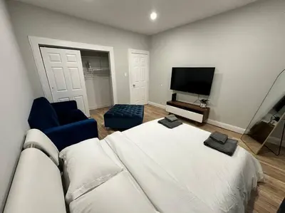 a bedroom with a white bed and a tv at Cozy 3 BR suite, 15 min to NYC &Times Sq in North Bergen