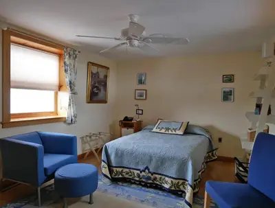 a bedroom with a bed and two blue chairs at Idea Farm in Callicoon Center