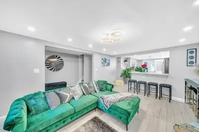 a living room with a green couch and a kitchen at 3 Bedroom Duplex w Large Backyard in Brooklyn