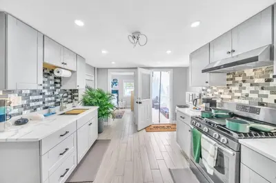 a large white kitchen with white cabinets and appliances at 3 Bedroom Duplex w Large Backyard in Brooklyn