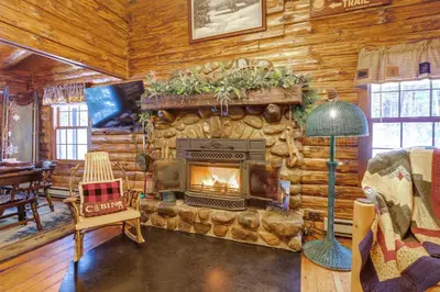 a living room with a fireplace in a log cabin at Lake and Beach Access at Lake Luzerne Cabin! in Lake Luzerne