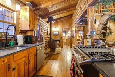 a kitchen with wooden cabinets and a stove at Lake and Beach Access at Lake Luzerne Cabin! in Lake Luzerne
