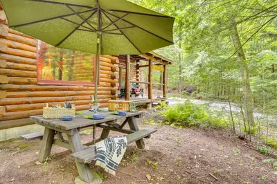 a picnic table with an umbrella in front of a cabin at Lake and Beach Access at Lake Luzerne Cabin! in Lake Luzerne
