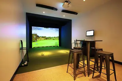 a room with two bar stools and a large screen television at Blueground Hudson Yards gym rock wall arcade NYC-1453 in New York
