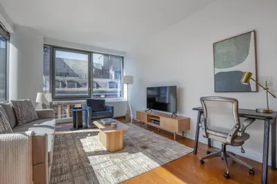 a living room with a couch and a desk and a tv at Blueground Hudson Yards gym rock wall arcade NYC-1453 in New York