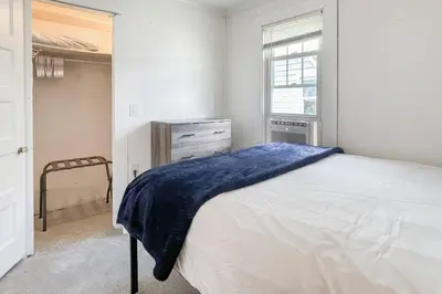 a bedroom with a bed and a dresser and a window at Beachside in Branford in Stamford