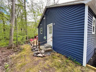 a blue house in the middle of the woods at Bear Run Bungalow in Hawley