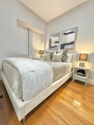 a white bedroom with a large bed and a table at Dream Home Close to the Center of NYC in Mott Haven