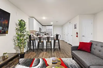 a living room with a couch and a kitchen at Family & Traveler Haven - NYC & NWK w/free parking in Newark