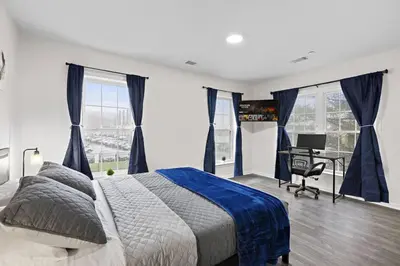 a bedroom with a bed and a desk and windows at Home Sweet Home - near NWK & NYC w/free parking in Newark