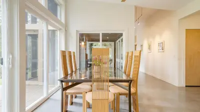 a dining room with a glass table and chairs at Secluded Modern Enclosed Patio Forest Views Woodland Zen by AvantStay in Stockbridge