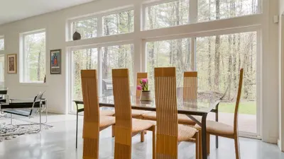 a dining room with a glass table and chairs at Secluded Modern Enclosed Patio Forest Views Woodland Zen by AvantStay in Stockbridge