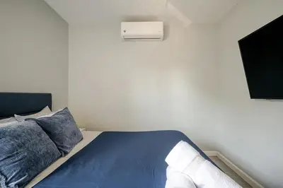 a bedroom with a blue bed and a television at Modern 3-Bdrm Apt in Black Rock in Bridgeport