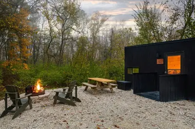 a black tiny house with a picnic table and a fire at Postcard Cabins Machimoodus, Outdoor Collection by Marriott Bonvoy in Moodus