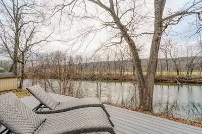 two chairs sitting on a wooden deck next to a river at Brand New House with Large Porch in Lake Katrine in Lake Katrine