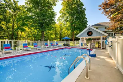 a swimming pool with blue chairs and a white fence at Massive Roscoe Retreat Great for Large Groups! in Roscoe