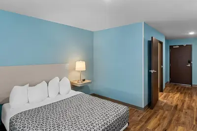 a bedroom with a white bed and a blue wall at WoodSpring Suites Newington - Hartford South in Newington