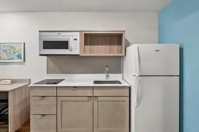 a kitchen with a white refrigerator and a sink at WoodSpring Suites Newington - Hartford South in Newington