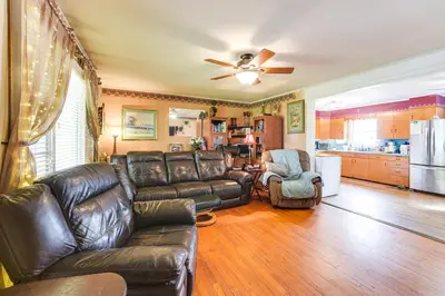 a living room with a leather couch and a kitchen at Cozy Ballston Spa Home with Fenced Yard! in Malta