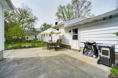 a patio with a grill and chairs and an umbrella at Cozy Ballston Spa Home with Fenced Yard! in Malta