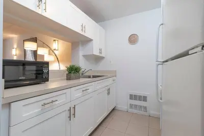 a kitchen with white cabinets and a refrigerator at Central Park North - Quiet Place in New York
