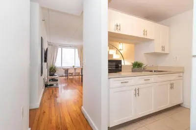 a kitchen with white cabinets and a hard wood floor at Central Park North - Quiet Place in New York