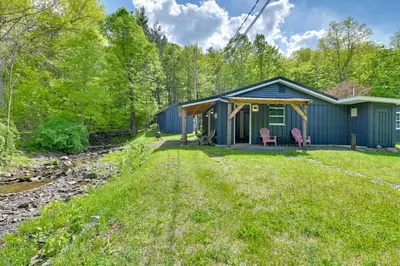 a blue cottage with two pink chairs in the yard at Cozy Catskills Cabin - 12 Mi to Windham Mountain! in East Durham