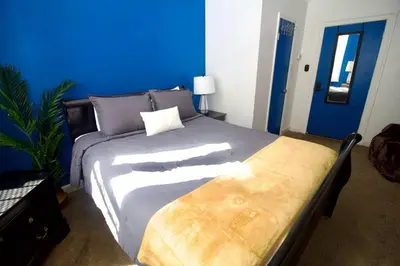 a bedroom with a large bed with a blue wall at Tuk Ahoy - Sapphire Suite 1B with Shared Spaces in Brooklyn