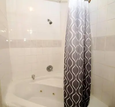 a bathroom with a bath tub with a shower curtain at Tuk Ahoy - Sapphire Suite 1B with Shared Spaces in Brooklyn
