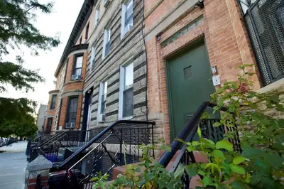 a building with a green door on a street at Tuk Ahoy - Sapphire Suite 1B with Shared Spaces in Brooklyn