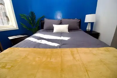a bedroom with a large bed with a blue wall at Tuk Ahoy - Sapphire Suite 1B with Shared Spaces in Brooklyn