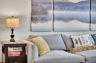 a living room with a couch and four paintings on the wall at Saratoga Guest House in Saratoga Springs