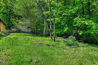 a yard with green grass and trees and a house at Saratoga Guest House in Saratoga Springs