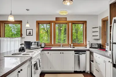 a kitchen with white cabinets and a sink and windows at Saratoga Guest House in Saratoga Springs