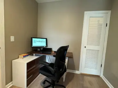 a desk with a computer and a chair in a room at NEW! Urban Oasis, Chic 3-BR 2-BA Corner Unit, Steps Away from NYC! in Jersey City