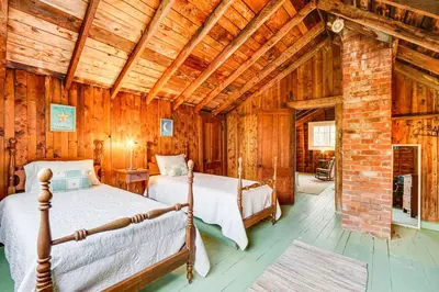 two beds in a room with wooden walls at 8 Mi to Mount Snow Rustic Marlboro Cottage in Brattleboro